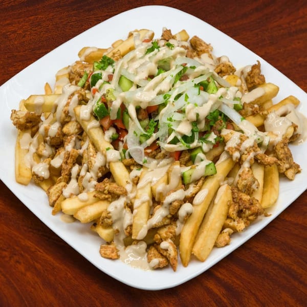 Sepan Chicken's loaded fries with chicken, vegetables, and creamy sauce on a white plate.