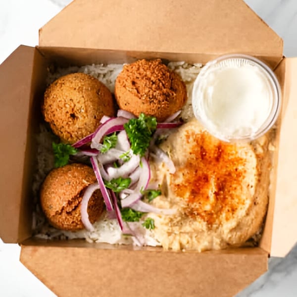 Sepan Chicken Mediterranean falafel, rice, hummus, red onions, and parsley in a takeout box.