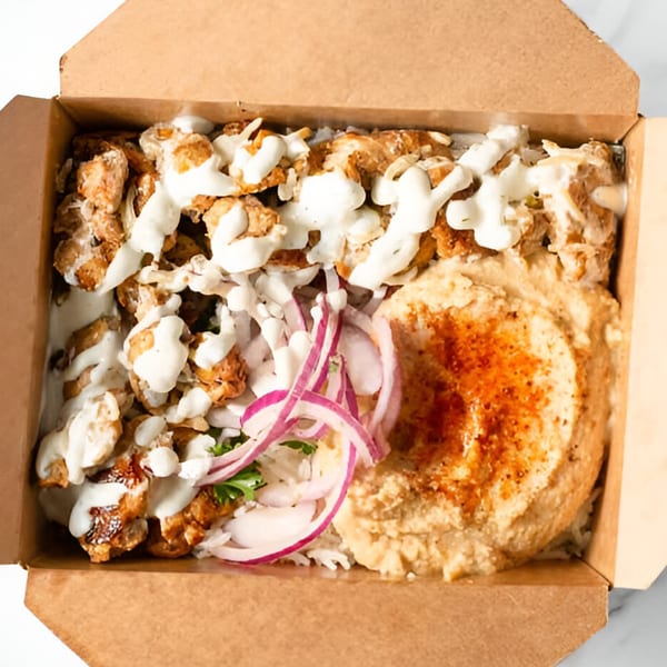 Sepan Chicken Mediterranean bowl with chicken, hummus, rice, red onions, and white sauce in a box.